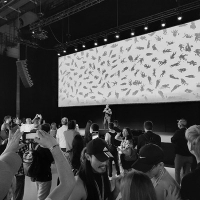 An audience photographing a wide screen showing the work