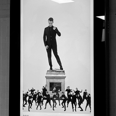 A poster of the work beside a statue